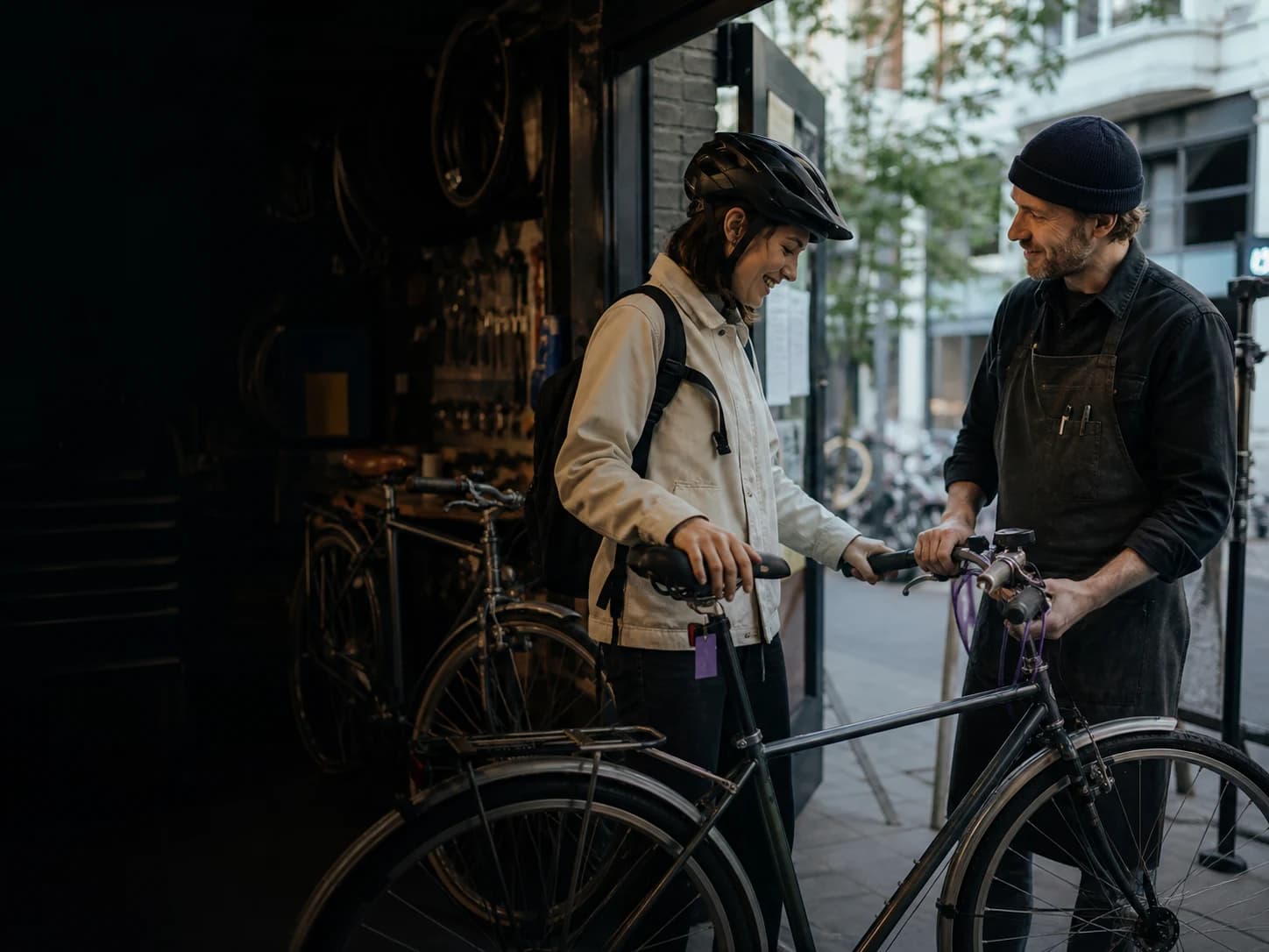 A bike shop owner handing a repaired bicycle back to its rider