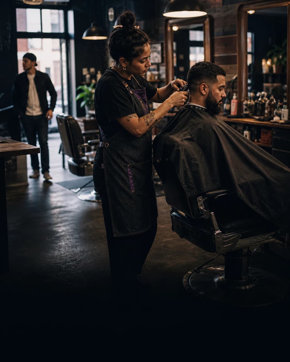A barbershop owner focused on a customer while the marketing work is handled